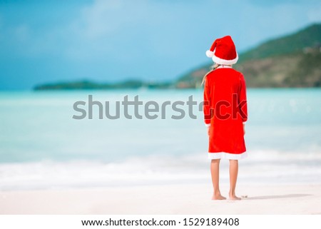 Adorable little girl in Santa hat on Christmas holidays on the beach