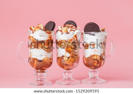 Sweet dessert in glass with biscuit and whipped cream on pink bsckground, selective focus and blank space.