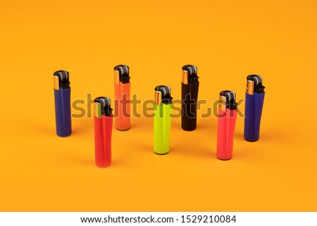 Multicolor gas lighters on orange background Royalty-Free Stock Photo #1529210084