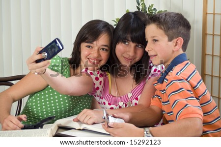 Three kids taking a picture of themselves with a cell phone.