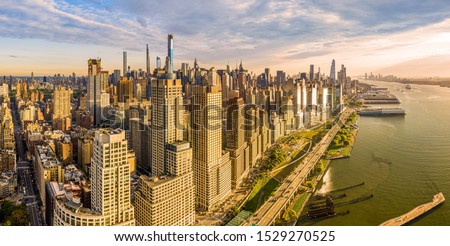 Aerial panorama of New York City waterfront skyline at sunset viewed from above River Side Park, along Joe DiMaggio highway and Riverside Blvd, next to Hudson River. Royalty-Free Stock Photo #1529270525