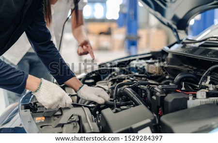 Mechanic asian man examining and maintenance to customer the engine a vehicle car hood, Safety inspection test engine before customer drive on a long journey, transportation repair service center