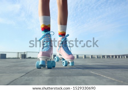 Young woman with vintage roller skates in city on sunny day, closeup view