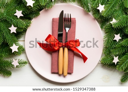 Top view of cutlery and plate on festive wooden background. New Year family dinner concept. Fir tree and Christmas decorations.