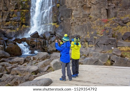 Two children, enjoying a sunny day in Thingvellir National Park rift valley,taking pictures with cellphones, Iceland autumntime