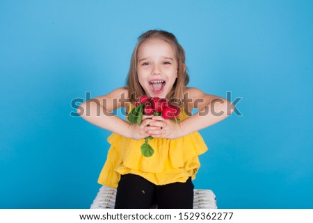 little girl with edible vegetables on a blue background