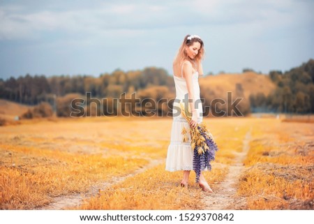 Beautiful girl with a bouquet of blue flowers on nature in autumn
