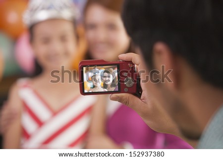 Father Taking a Picture of Mother and Daughter on Daughter's Birthday