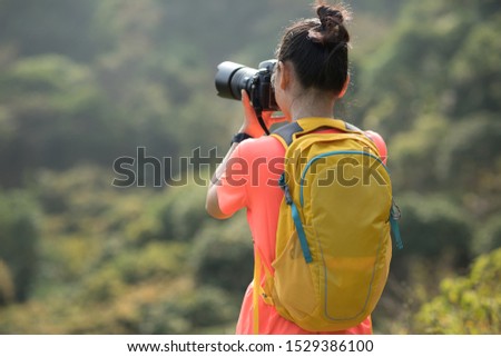 Woman photographer taking pictures in autumn forest