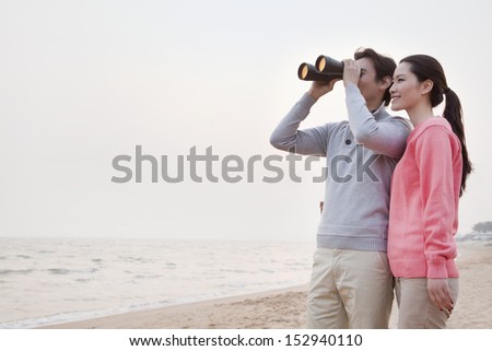 Young Couple Looking at the Ocean with Binoculars
