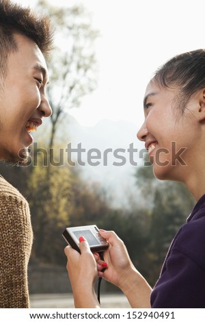 Young couple smiling, woman holding digital camera