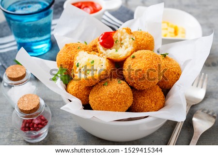 Homemade Fried Risotto Arancini stuffed with cheese, served with tomato sauce. Royalty-Free Stock Photo #1529415344