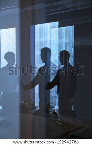 Reflection of two businessmen shaking hands