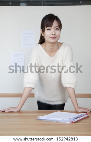 Young businesswoman standing with her hands on the table, portrait