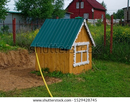 well in the form of a house in the garden in summer, Russia
