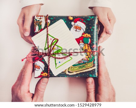 Hands of a child and an adult male, bright, colorful gift boxes. Merry Christmas and Happy New Year