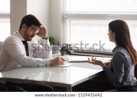Confused male hr manager listening to female job applicant at interview. Young woman making bad first impression on doubtful company recruiter. Employer unsure about working experience of candidate. Royalty-Free Stock Photo #1529435642