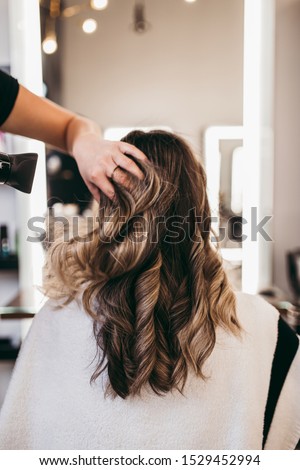 Beautiful brunette woman with long hair at the beauty salon getting a hair blowing. Hair salon styling concept. Royalty-Free Stock Photo #1529452994