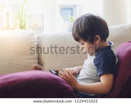 Indoor portrait kid with a happy face playing game on tablet, Close up face Cute boy having fun watching cartoons on digital taplet,Kid with smiling face playing games on touch pad