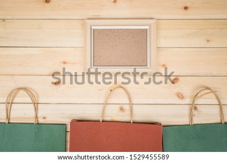 Green, red and colourful shopping bags with picture frame on wooden table.