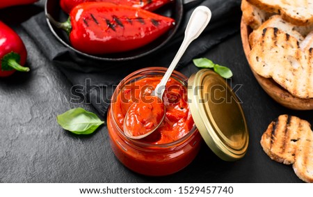 Grilled red pepper sauce (lutenica)  in glass jar with toasted bread.