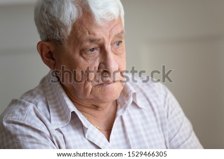 Face of senior caucasian hoary man looking away deep in sad thoughts feels lonely close up portrait, recollect memories and life moments, depressed grandfather alone indoors, yearning for wife concept Royalty-Free Stock Photo #1529466305