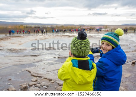 Children, taking picture of Strokkur Geysir while erupting, Iceland autumntime