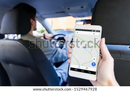 Closeup female hand is holding smartphone with online map on screen, shows way to home. Woman is riding on back seat of automobile car. Taxi booking application, mobile GPS navigator concept. Royalty-Free Stock Photo #1529467928