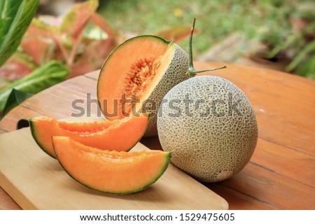 Two sliced and whole of Japanese melons,honey melon or cantaloupe (Cucumis melo) on wooden table background.Favorite fruit in summer.Food,Fruits or healthcare concept. Royalty-Free Stock Photo #1529475605