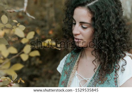 Young woman, dressed in casual clothes, with relaxed attitude, in a forest with autumn colors.