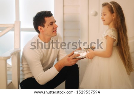 Father with daughter in Christmas time. Dad give a present for his little cure daughter