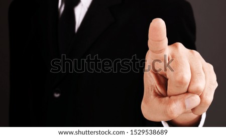 Man without head standing and shows outstretched hand with Pointing Finger on dark background. COPY SPACE.