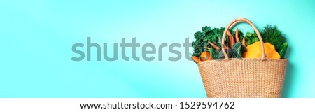 Straw basket with organic vegetables over trendy green background. Healthy food, vegetarian diet. Eco friendly, zero waste, plastic free concept