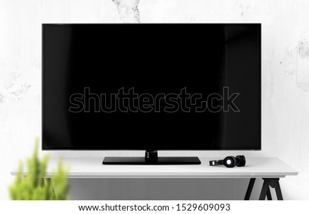 Big smart TV with headphones on table. Royalty-Free Stock Photo #1529609093