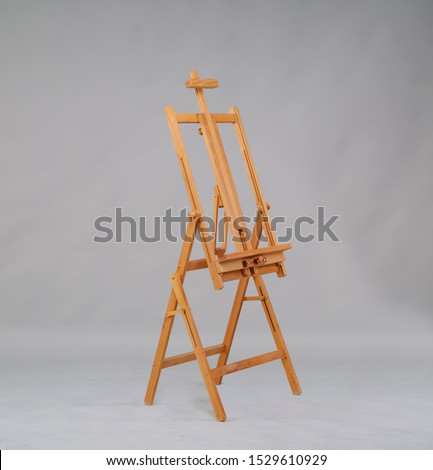 Wooden easel in the studio on a gray background.