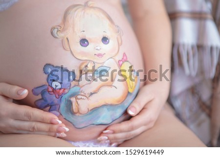 Nice drawing on the stomach of a pregnant woman in the form of a cheerful baby