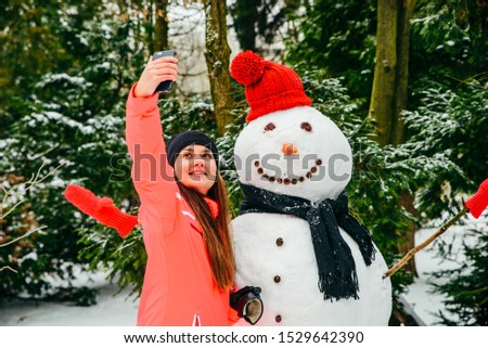pretty woman taking selfie with snowman