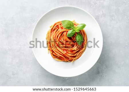 Top view of plate with spaghetti in tomato sauce and basil on white background Royalty-Free Stock Photo #1529645663