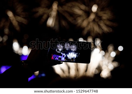 Silhouette of hands with mobile cell phone to take a photo of fireworks