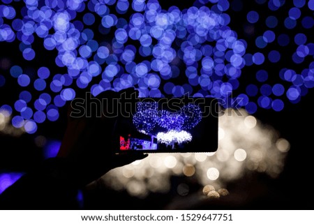 Silhouette of hands with mobile cell phone to take a photo of fireworks