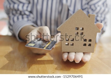 House model and a credit card is picked up. The idea of selling via installments from credit card.