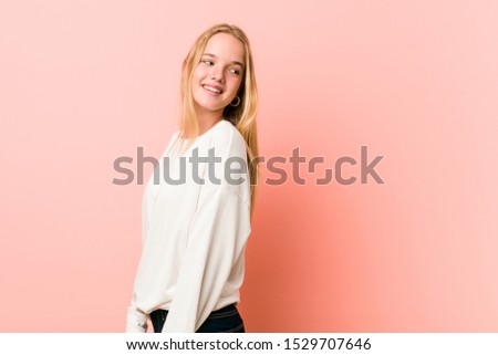 Young blonde teenager woman looks aside smiling, cheerful and pleasant.