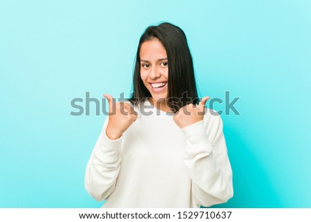Young pretty hispanic woman raising both thumbs up, smiling and confident.