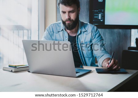 Busy IT specialist working on project at workplace. Office manager using digital devices for job. Man typing on laptop and tablet. Guy getting distant education, watching webinar, video, learning info