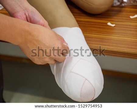 Orthopedic surgeon demonstrates stump elastic bandaging on a model for a below-knee amputation patient. Healthcare and medical education.