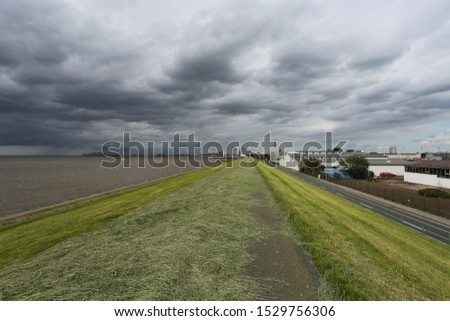The coastline a mowed grass of gently green in Germany Bremerhaven color with heavy gray clouds on a background