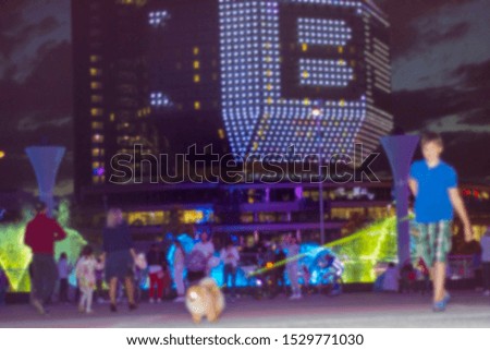 blurred image of people near colorful water fountains. Abstract background.  Selective foccus