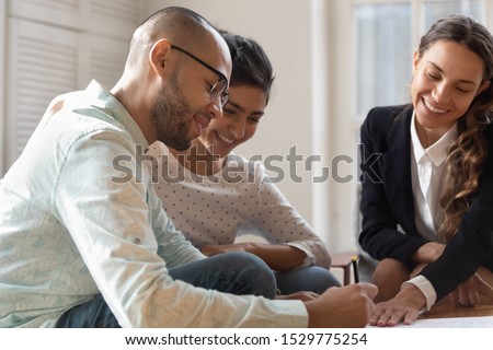 Happy diverse couple satisfied clients making successful deal with realtor, mortgage insurance broker, African American husband signing documents, family purchasing new apartment, taking loan,