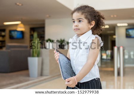 The cute girl in business clothes with a tablet in a business center