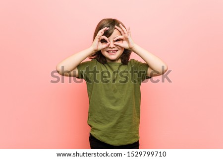 Little boy showing okay sign over eyes